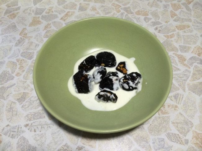 Alternar capes de crema agra i fruits secs a les prunes.